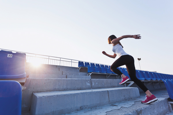 Woman running up stadium stairs. Practice makes perfect.